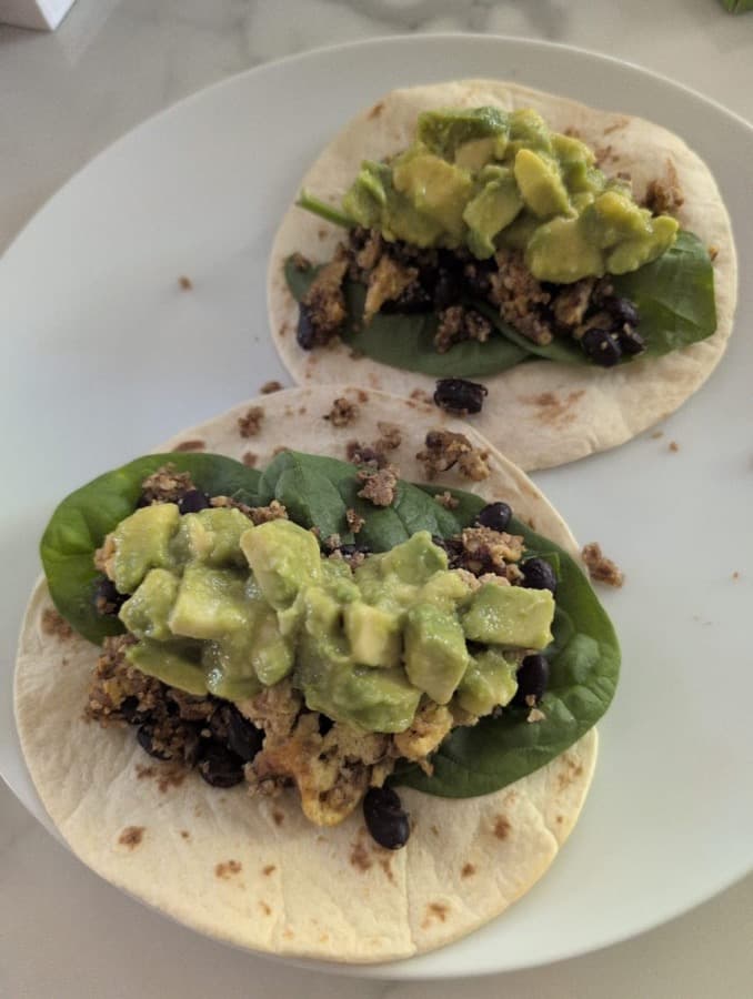 Two tacos with spinach and avocado